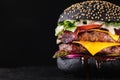 Yummy black burger grilled with double meat cutlet and melted cheese on a black background. Royalty Free Stock Photo