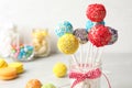 Yummy bright cake pops in glass jar full of marshmallows on table Royalty Free Stock Photo