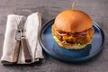 Yummy chicken burger with cheese on a blue round plate and cutlery on side Royalty Free Stock Photo