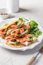 Yummy crepes or thin pancakes with smoked salmon, soft cheese and spinach on a plate close up on gray textured Royalty Free Stock Photo