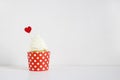 Yummy cupcake with red paper heart decoration on white table. Birthday, wedding or Valentine party food. Love concept.