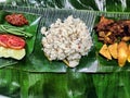 A Yummy Delight: A Nasi Liwet on a Banana Leaf with a Fried Chicken, Tomato,Spicy Sambal, Cucumber, Green Peas, Tofu, and Tempeh