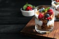 Yummy dessert with granola, yogurt and berries on dark table, space for text