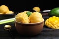 Yummy mango ice cream in bowl on black wooden table