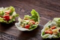 Yummy top view composition of fresh healthy salad served in lettuce leaves on wooden table. Royalty Free Stock Photo