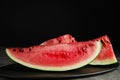 Yummy watermelon slices on grey table against black background Royalty Free Stock Photo