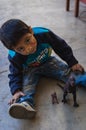 Yungay, Peru, August 4, 2014: Latino little boy with indigenous features with a dirty face of paint playing with t-rex toys