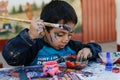 Yungay, Peru, August 4, 2014: portrait of happy naughty boy with paint stained face, clothes and hands doing crafts with brush Royalty Free Stock Photo