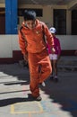 Yungay, Peru, August 8, 2014: portrait of indigenous boy with orange tracksuit jumping playing hopscotch and girl behind looking Royalty Free Stock Photo