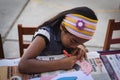Yungay, Peru, August 4, 2014: portrait of small latin girl with concentrated headband making a craft mask