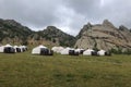 Yurt camp surrounded by trees on the ridge of the mountain. Small ger huts on the crest of the hill on a cloudy day