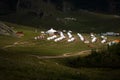 Yurt camp surrounded by trees on the ridge of the mountain. Small ger huts on the crest of the hill on a sunny day