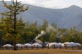 Yurt camp surrounded by trees on the ridge of the mountain. Small ger huts on the crest of the hill on a sunny day