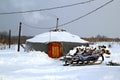 An yurt with the sleigh on a white snow.