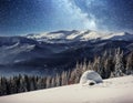 Yurt in the snow in the winter forest. Starry sky over the mountain peaks