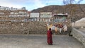 Tibetan monk praying in front of Mani stones at the Mani Temple Mani Shicheng wall with buddhist mantra Om Mani Padme Hum engrav Royalty Free Stock Photo