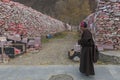 Tibetan monk walking in front of Mani stones wall with buddhist mantra Om Mani Padme Hum engraved in Tibetan in Yushu, China Royalty Free Stock Photo