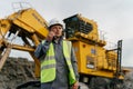 A miner in a helmet talking over the radio in front of a Komatsu PC4000 excavator.
