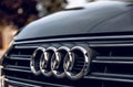 Close-up photo of audi logo on grille of dark gray car.