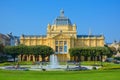 Art Pavilion in Zagreb, Croatia. Yellow building with water fountain, green lawn and trees in front, clear sky Royalty Free Stock Photo