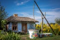 ZALIPIE, POLAND - August 1, 2021:A small, white wooden cottage and a traditional well, painted in colorful flowery pattern