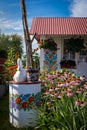 ZALIPIE, POLAND - August 1, 2021: A white well painted in colorful floral pattern, a bucket and a swan statue on top.