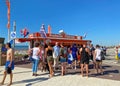 Dutch waterfront promenade with typical fish sale booth, people standing, north sea beach background, blue summer sky