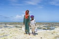 African children collect mollusks at low tide on the coast of Zanzibar, Tanzania, East Africa