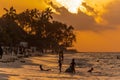 Zanzibar, Tanzania - 05 January 2021: Beautiful tropical sunset with palm trees and peoples silhoette at beach