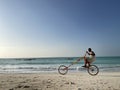 Zanzibar, - Tanzania, January 10, 2021: Young black man smiling and riding a self maiden funny bright long bicycle with Indian