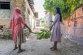 Two african young girls carry a bunch of green bananas on the street of Zanzibar island, Tanzania, East Africa