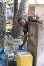 African boy fills the canister with tap water on a street in Zanzibar Island, Tanzania, East Africa Royalty Free Stock Photo