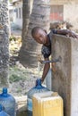 African boy fills the canister with tap water on a street in Zanzibar Island, Tanzania, East Africa Royalty Free Stock Photo