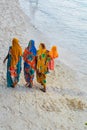 Zanzibar women walk on sandy beach. Tanzania