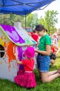 Young woman - volunteer and girl - participating at art and craft outdoors workshop