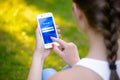 ZAPORIZHZHYA, UKRAINE - SEPTEMBER 20, 2014: Young Woman Using Facebook Social Network Application on her Smart Phone