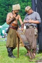 Zaporozhian Sich cossack and his squire load ozhyga, ancient machine gun with bullets and gunpowder