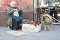 Zaporozhye. Ukraine. October 9 2019. Homeless lonely woman, holds an icon, feeds a stray dog