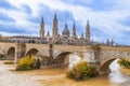 Zaragoza landscape with ancient Stone Bridge over Ebro river with yellow water Royalty Free Stock Photo