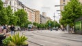 Zaragoza, Spain - April 29, 2023: Wide avenue full of people walking and tram circulating on the street.