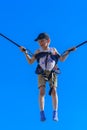 Zarechany, Ukraine - June 10, 2018. Children jumping on a trampoline with rubber ropes against the blue sky. Adventures and