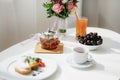 Zavrnik with tea on a wooden stand with wedding rings on a white table with a plate, cup and bowl with grapes. Royalty Free Stock Photo