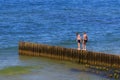 ZELENOGRADSK, KALININGRAD REGION, RUSSIA - JUNE 18, 2019: Two unknown boys on the wooden breakwater on the Baltic Sea coast in Royalty Free Stock Photo