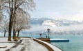 Zell am See in winter. Esplanade along Lake Zell, snow, frozen trees and misty mountain in alpine town. Famous ski