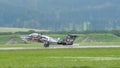 Military plane with cat livery lands at an alpine airport in a green valley Royalty Free Stock Photo