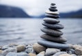 Zen balancing pebbles next to a misty lake.
