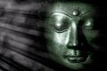 Zen buddhism and spiritual enlightenment. Mindful green toned buddha face mystical light Royalty Free Stock Photo