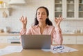 Zen concept. Lady freelancer meditating with eyes closed, dealing with stress while working with laptop in kitchen Royalty Free Stock Photo