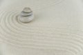 Zen garden. Pyramids of white and gray zen stones on the white sand with abstract wave drawings.