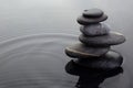 Zen stones in balanced pile in water on rippled water surface.